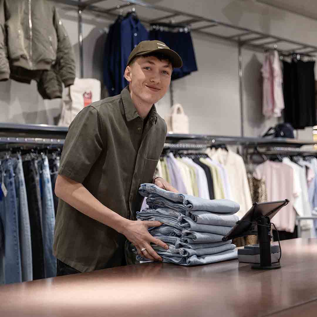 Employee from Samsøe Samsøe in Frederiksberg holding jeans.